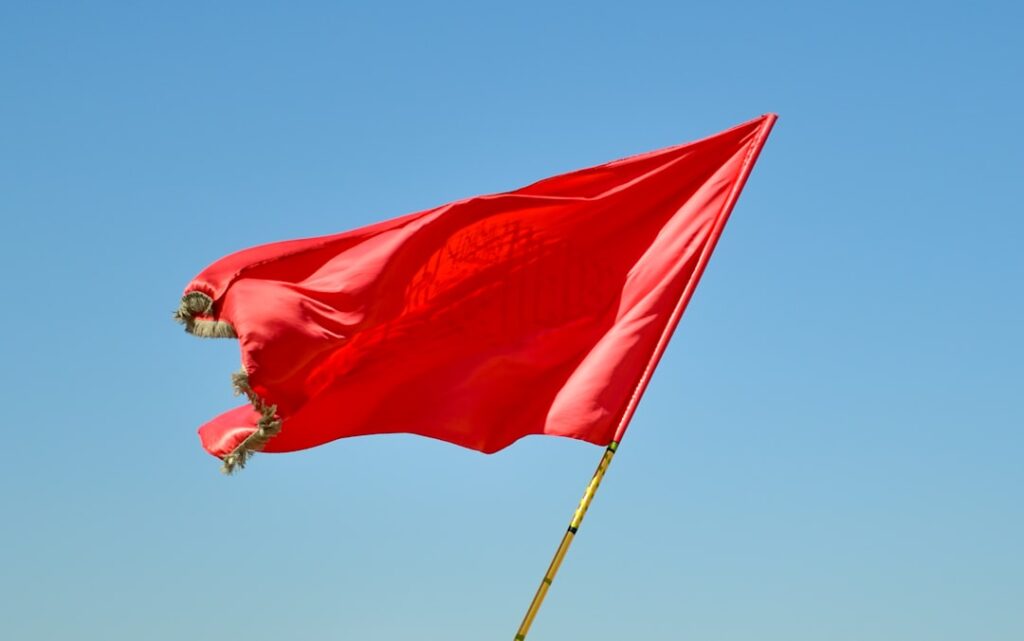 Red warning flag against blue sky symbolizing red flags to watch for when evaluating agencies