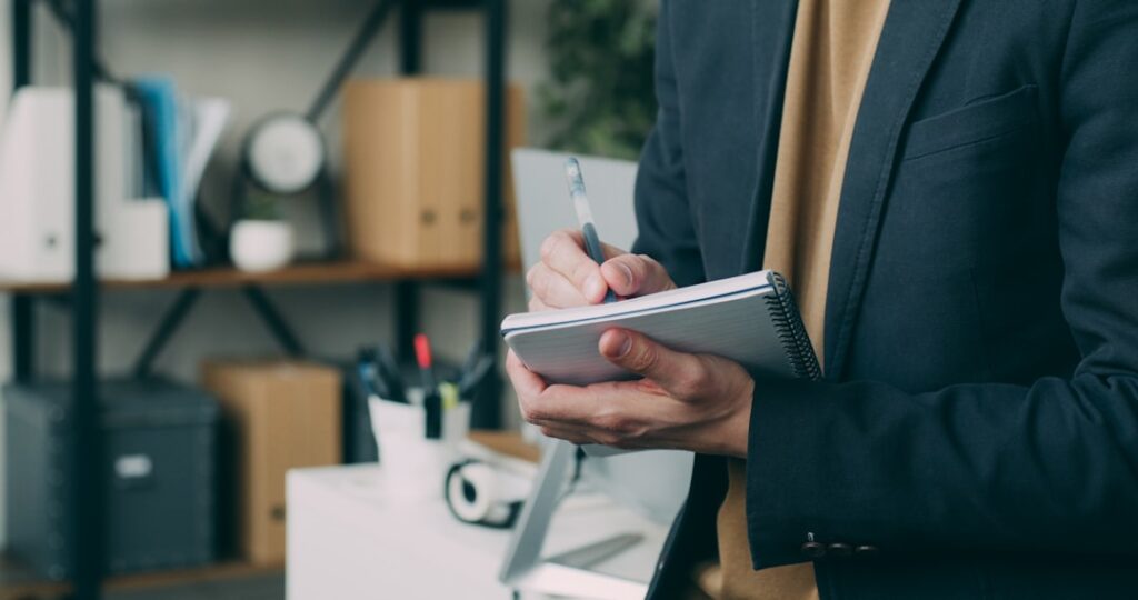 Business professional in suit writing notes on clipboard for interview preparation and planning